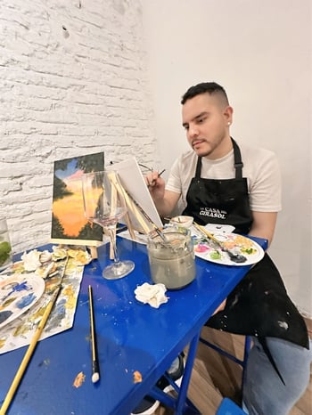 Raul painting with paint supplies on the table